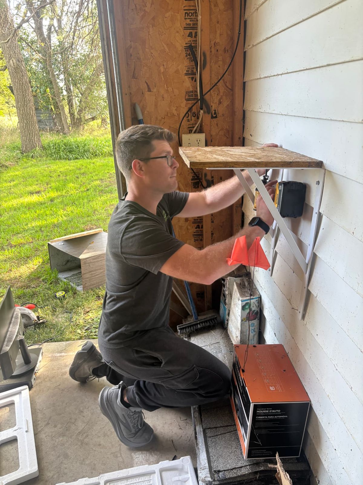 All Things Tech technician mounting a wall shelf for camera recording equipment in a garage