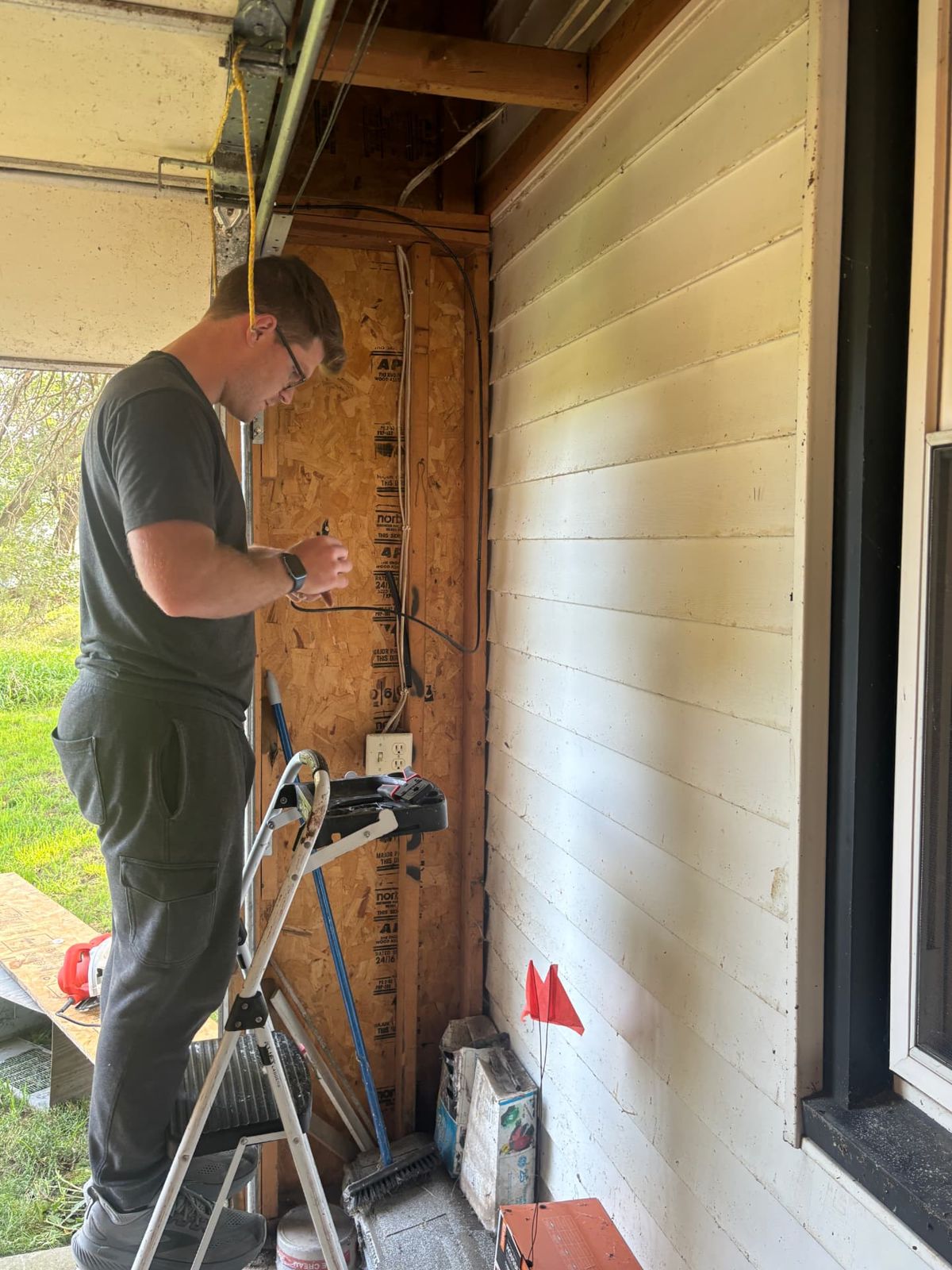 Technician preparing security camera wiring on a garage wall